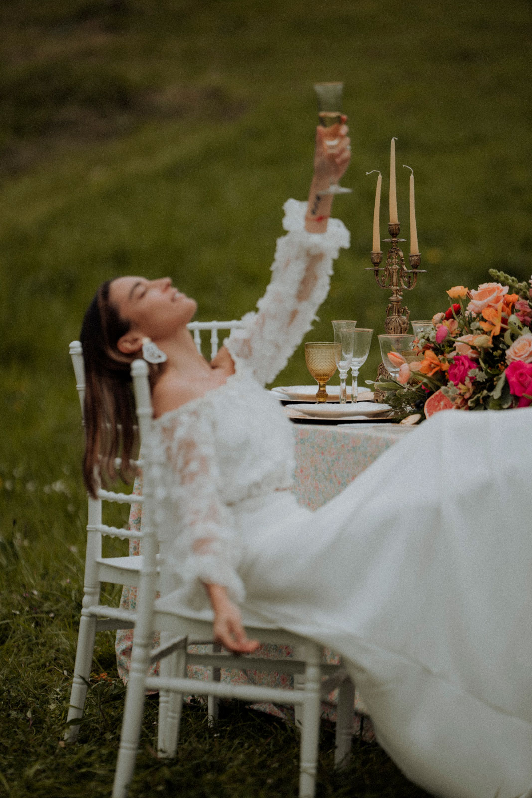 novia sentada en una mesa con flores bebiendo champan