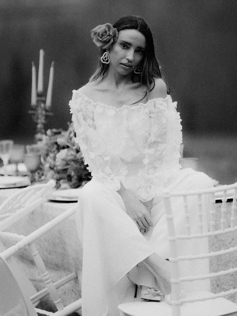 Una mujer vestida de novia sentada en una mesa de celebración en Blanco y negro
